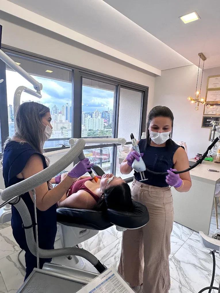 Dra. Taís atendendo uma paciente em consultório com vista para a cidade